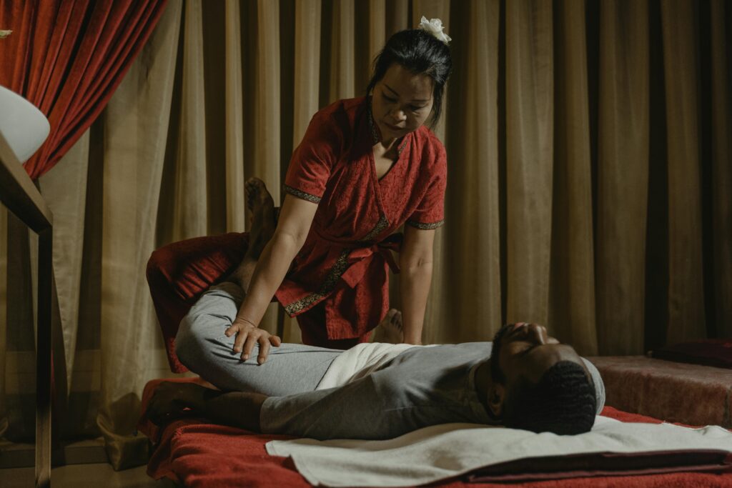 pexels-photo-6188113-6188113 Professional therapist performing leg stretch on client in a serene massage room setting.