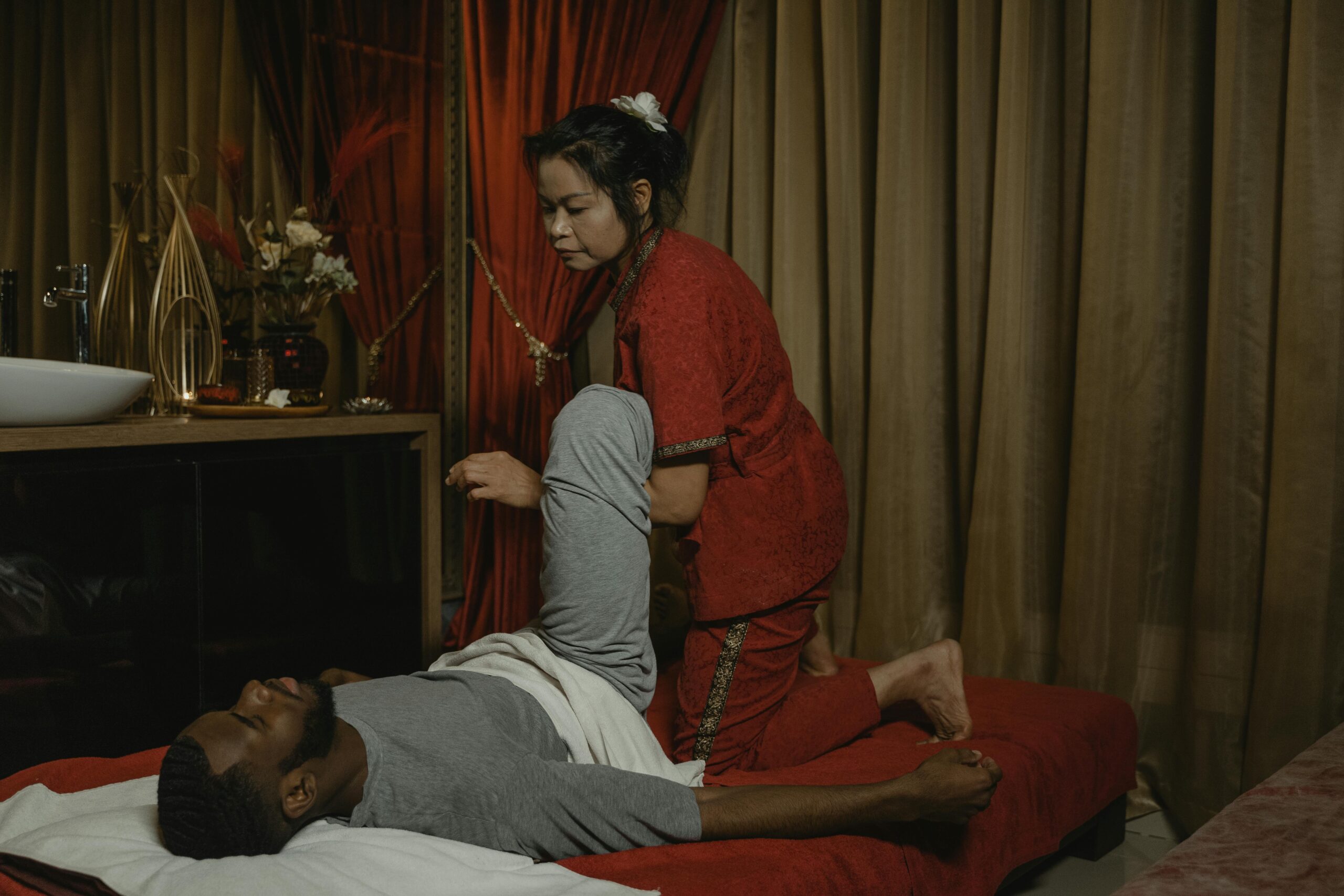 An adult man receiving a therapeutic massage from a professional masseuse in a calming indoor setting.